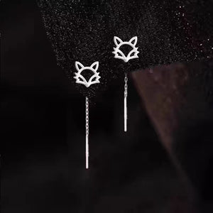 Silver fox-shaped earrings with chain details on a dark background
