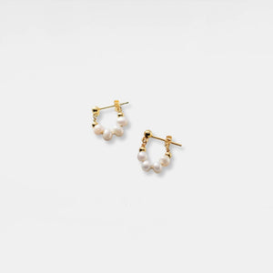 Pair of gold hoop earrings with pearl accents on a light gray background