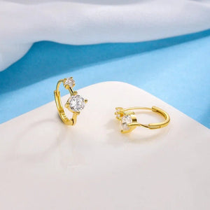 Gold hoop earrings with clear gemstones on a white and blue background