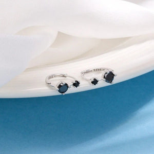 Silver rings with black gemstones on a white surface