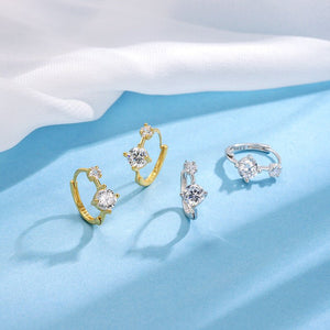 Gold and silver earrings with gemstones on a light blue fabric background