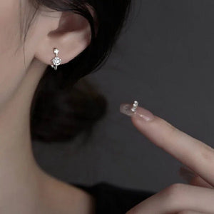 Close-up of a person wearing a silver earring with a dark background