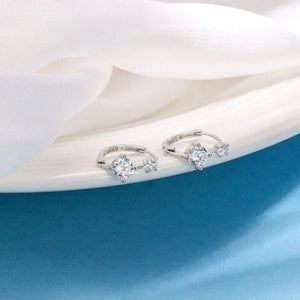 Pair of silver earrings with gemstones on a white and blue fabric background