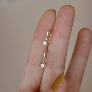 Gold ring with two diamond stones on a finger against a neutral background