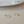A pair of small gold-colored huggie hoop earrings with a geometric design, displayed on a white surface.