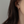 Close-up of an ear wearing a gold earring with a green gemstone against a neutral background