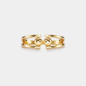 Gold ring with two spherical elements on a white background