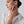 Woman wearing a gold ring on her finger, touching her neck against a plain background