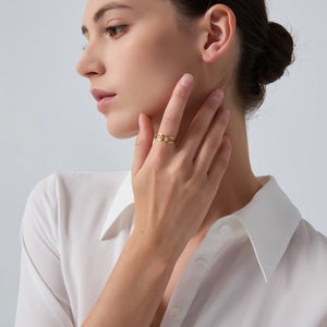Woman wearing a gold ring on her finger, touching her neck against a plain background