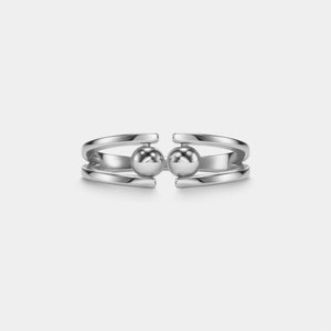 Silver ring with two spherical ends on a light gray background