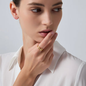 Woman wearing a gold ring on her finger against a plain background