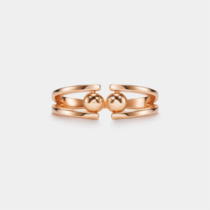 Rose gold ring with two spherical elements on a light gray background