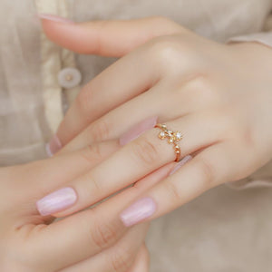 Close-up of a hand wearing a gold ring with a decorative design on a blurred background