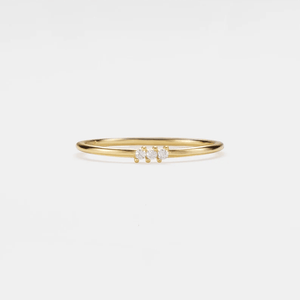 A set of thin gold-colored bands with green and clear cubic zirconia accents on a white background.