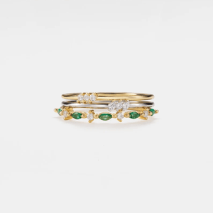 Stack of gold and silver rings with green gemstones on a white background