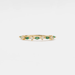 A set of thin gold-colored bands with green and clear cubic zirconia accents on a white background.