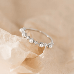 Silver earring with pearls on a beige stone background