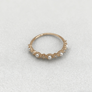 Gold ring with pearls on a light gray background
