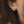 A close-up image of a woman's ear wearing a gold-colored stud earring with a cubic zirconia.