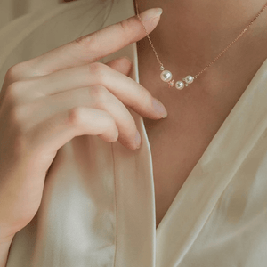 Pearl necklace being worn by a person with a neutral background