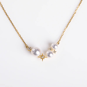 Pearl necklace with gold chain and star-shaped clasps on a white background