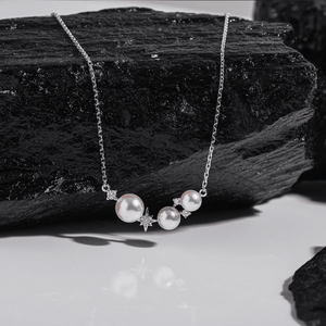 Pearl necklace with star accents on a dark stone surface