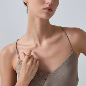 Woman wearing a beige lace camisole against a plain background