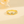 Gold ring with colorful gemstones on a beige background