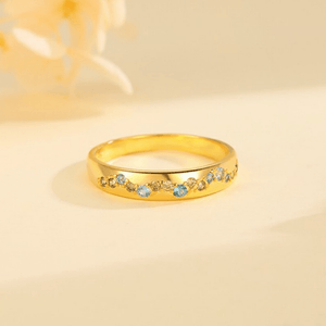 Gold ring with colorful gemstones on a beige background