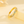 Gold ring with embedded colorful gemstones on a yellow background
