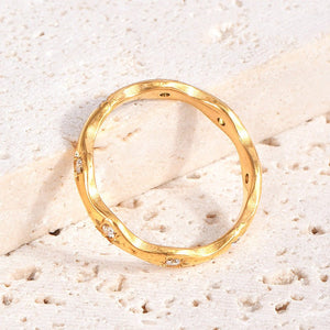 Gold star ring with small cubic zirconia on a textured beige surface