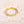 Gold star ring with small cubic zirconia on a textured beige surface