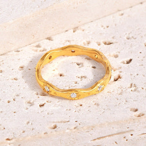 Gold star ring with small cubic zirconia on a textured beige surface