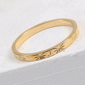 Gold ring with star patterns on a light gray background