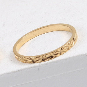 Gold ring with star patterns on a light gray background