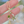 Gold necklace with green gemstones held by a hand against a blurred background
