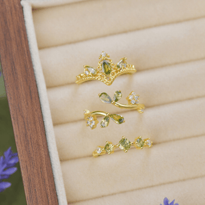 Gold and green gemstone jewelry set on a wooden box with floral background