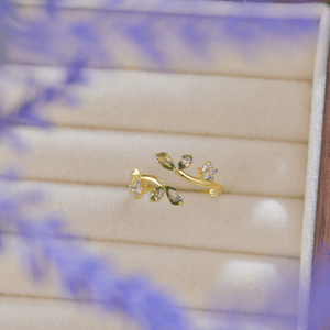 Gold earring with green gemstones on a wooden surface
