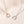 Two heart-shaped pendants on chains against a beige background