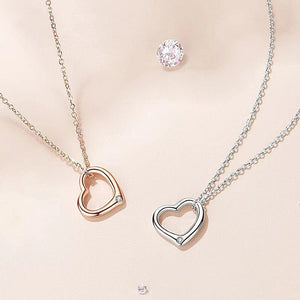 Two heart-shaped pendants on chains against a beige background