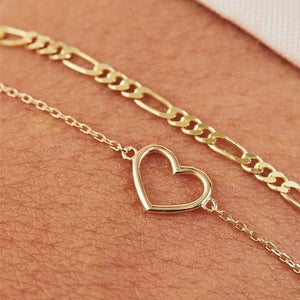 Gold heart-shaped bracelet on a person's wrist with a neutral background