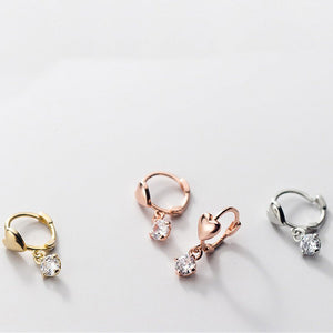 Three pairs of earrings in gold, rose gold, and silver on a light gray background