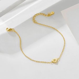 Gold bracelet with heart-shaped charms on a white surface