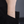 Gold bracelet with a heart charm on a wrist against a dark background