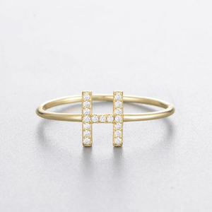 Gold ring with letter 'H' design on a light gray background