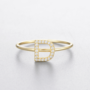 Gold ring with letter 'D' design on a light gray background
