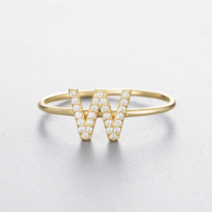 Gold ring with letter 'W' design on a light gray background