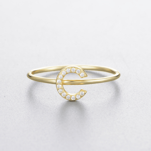 Gold ring with a letter 'C' design on a light gray background
