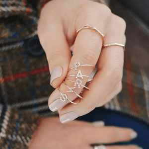 Close-up of a hand wearing multiple gold rings with intricate designs.