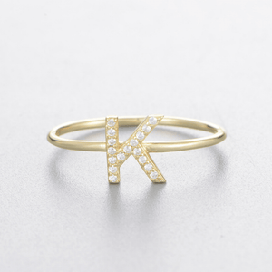 Gold bracelet with a letter 'K' design on a light gray background